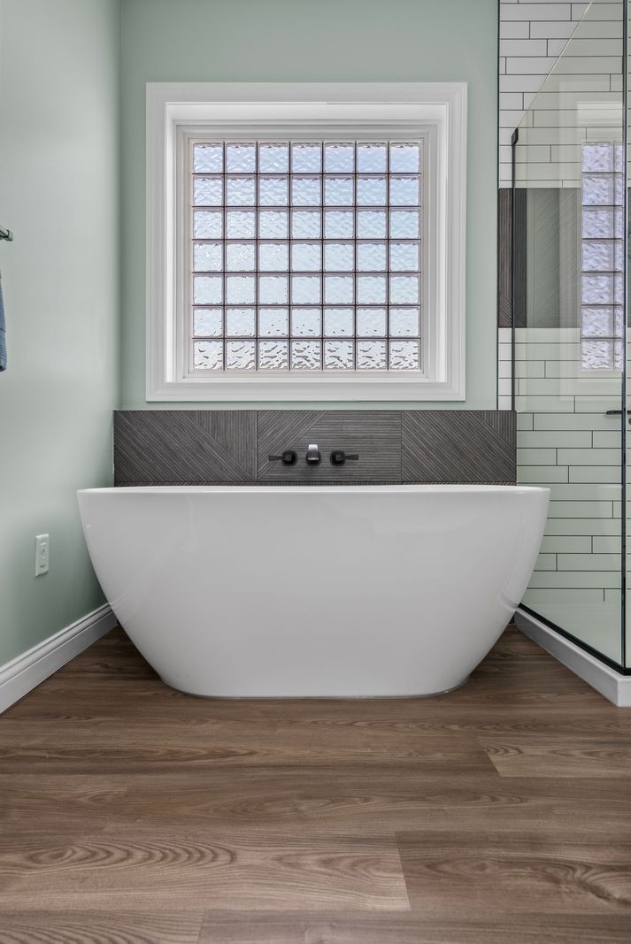 Freestanding soaking tub beneath a glass block window