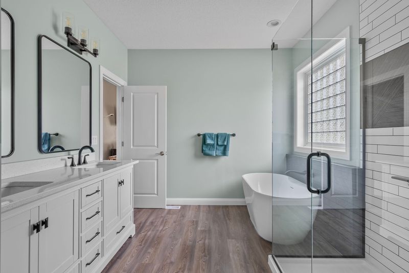 Bright remodeled bathroom with white vanity, freestanding tub and glass shower