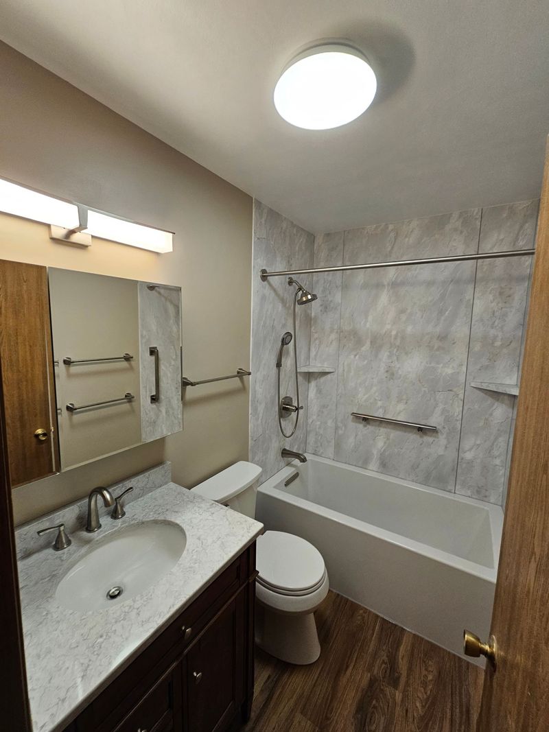 Remodeled tub and shower with gray acrylic walls and new vanity