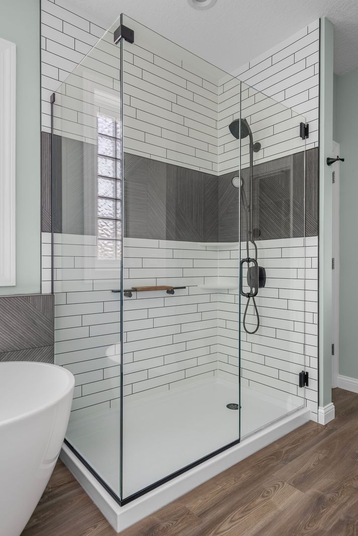 Glass walk-in shower with white subway-tile-look walls and gray accent band