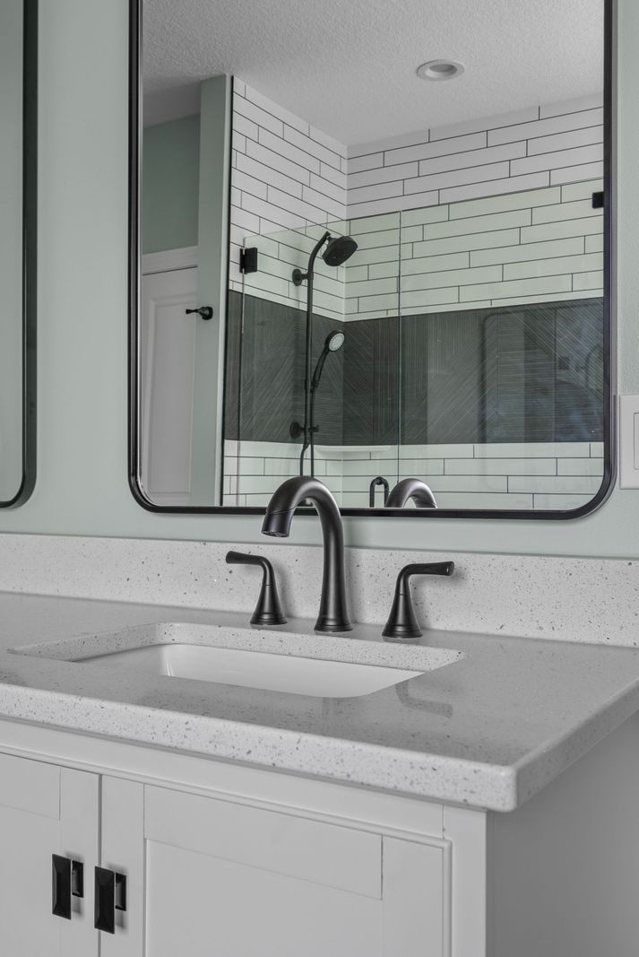White vanity with black mirror, subway-tile-look shower behind